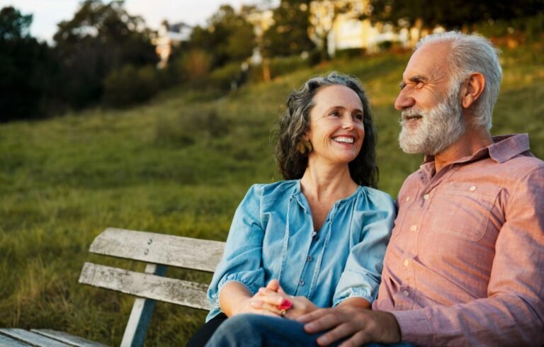 man and woman smiling while sitting in the bench